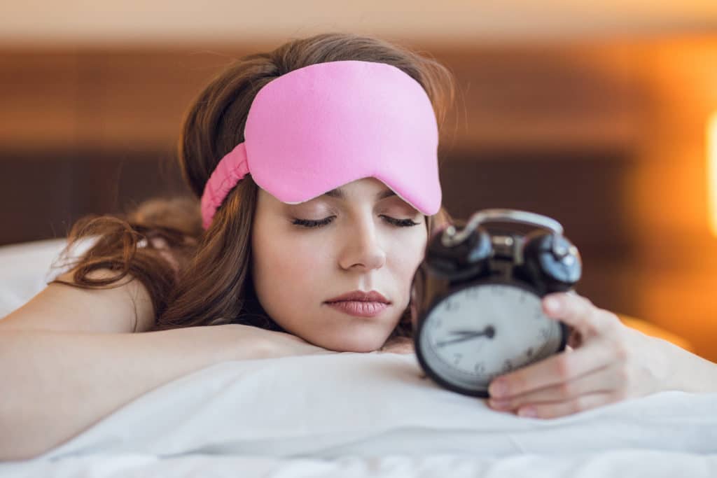 Schlafendes junges Mädchen mit einer Uhr