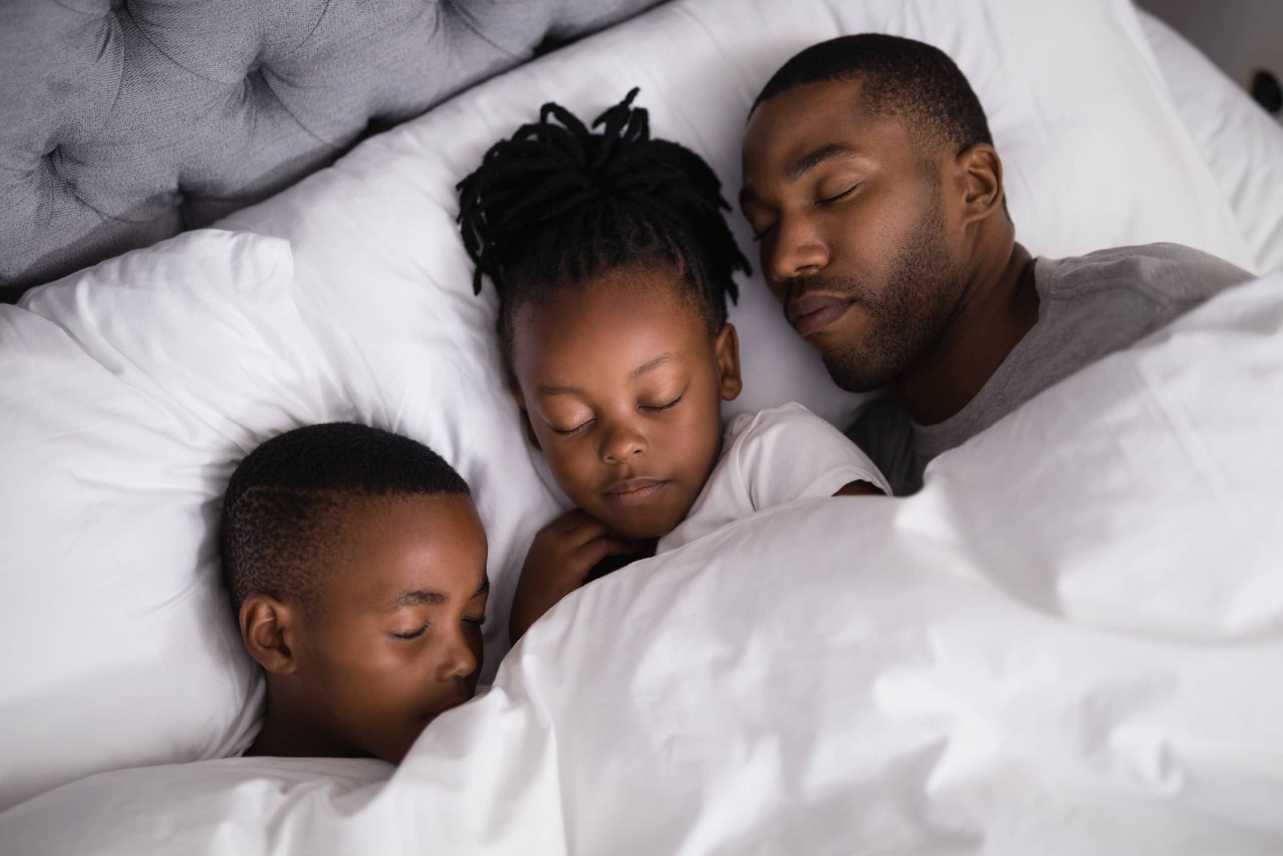 Vater mit Kindern schlafen zusammen auf dem Bett zu Hause