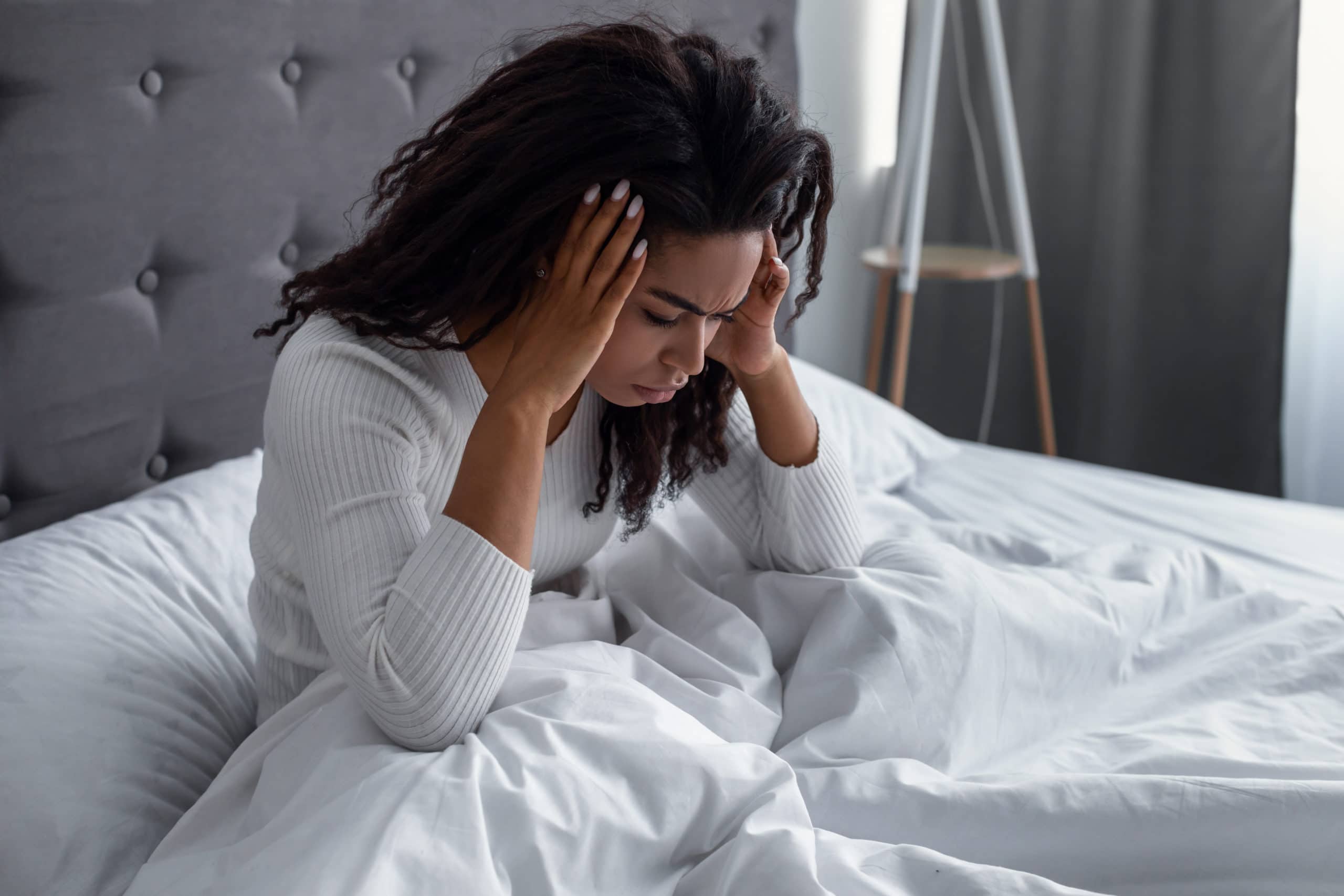 Frau, die unter Kopfschmerzen oder Migräne im Bett leidet