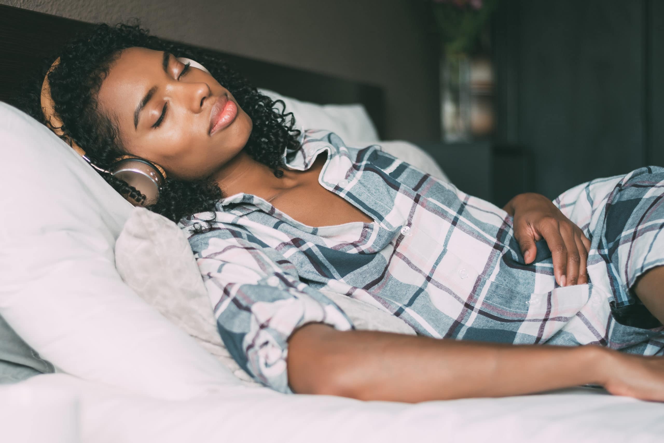 Frau schlafen auf dem Bett und hören Musik mit Kopfhörern und Smartphone
