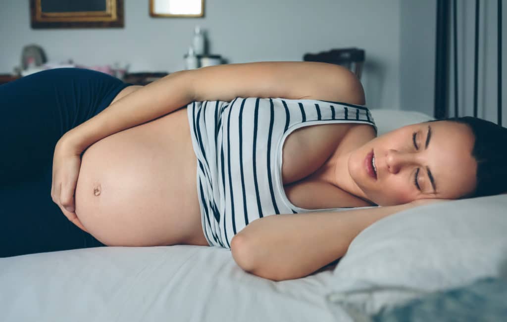 Schwangere Frau schläft im Bett