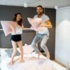 Paar kämpft mit Kissen im Schlafzimmer