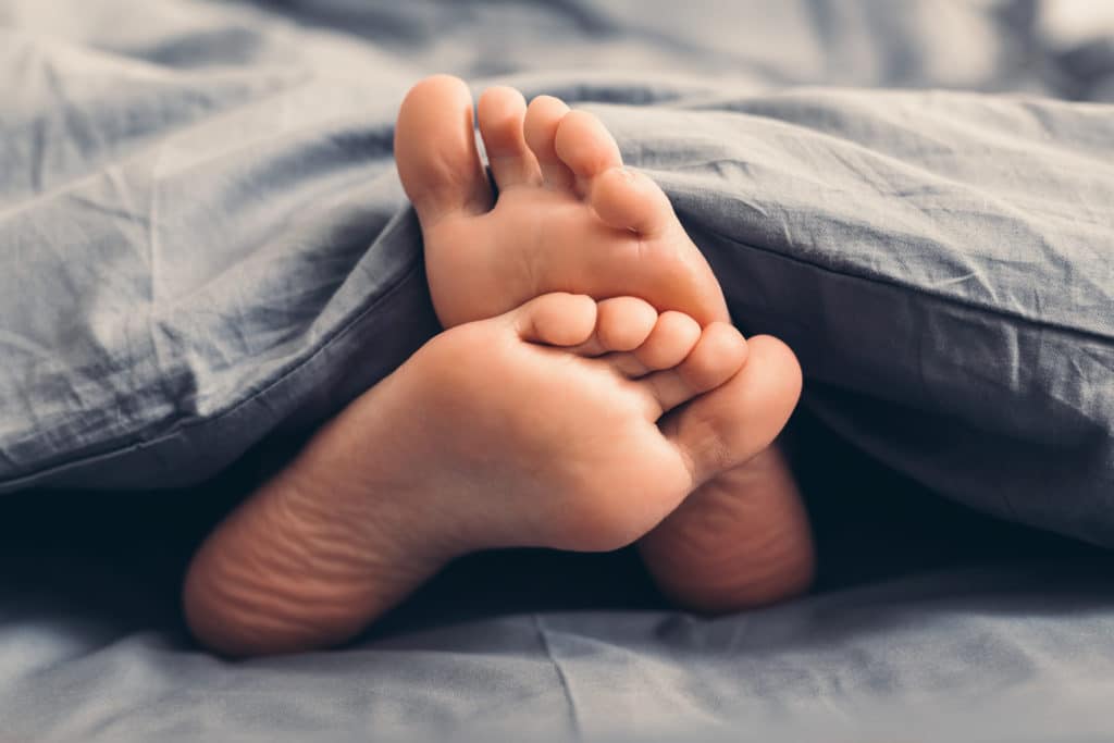 Weiblich schöne Füße unter Decke im Bett