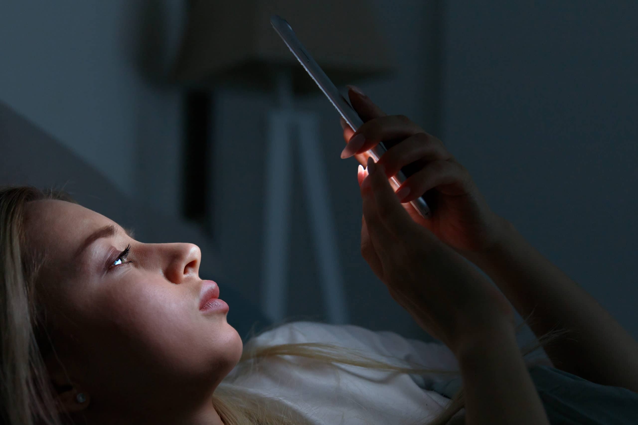 Gelangweilte Frau surft spät in der Nacht mit Smartphone im Interne