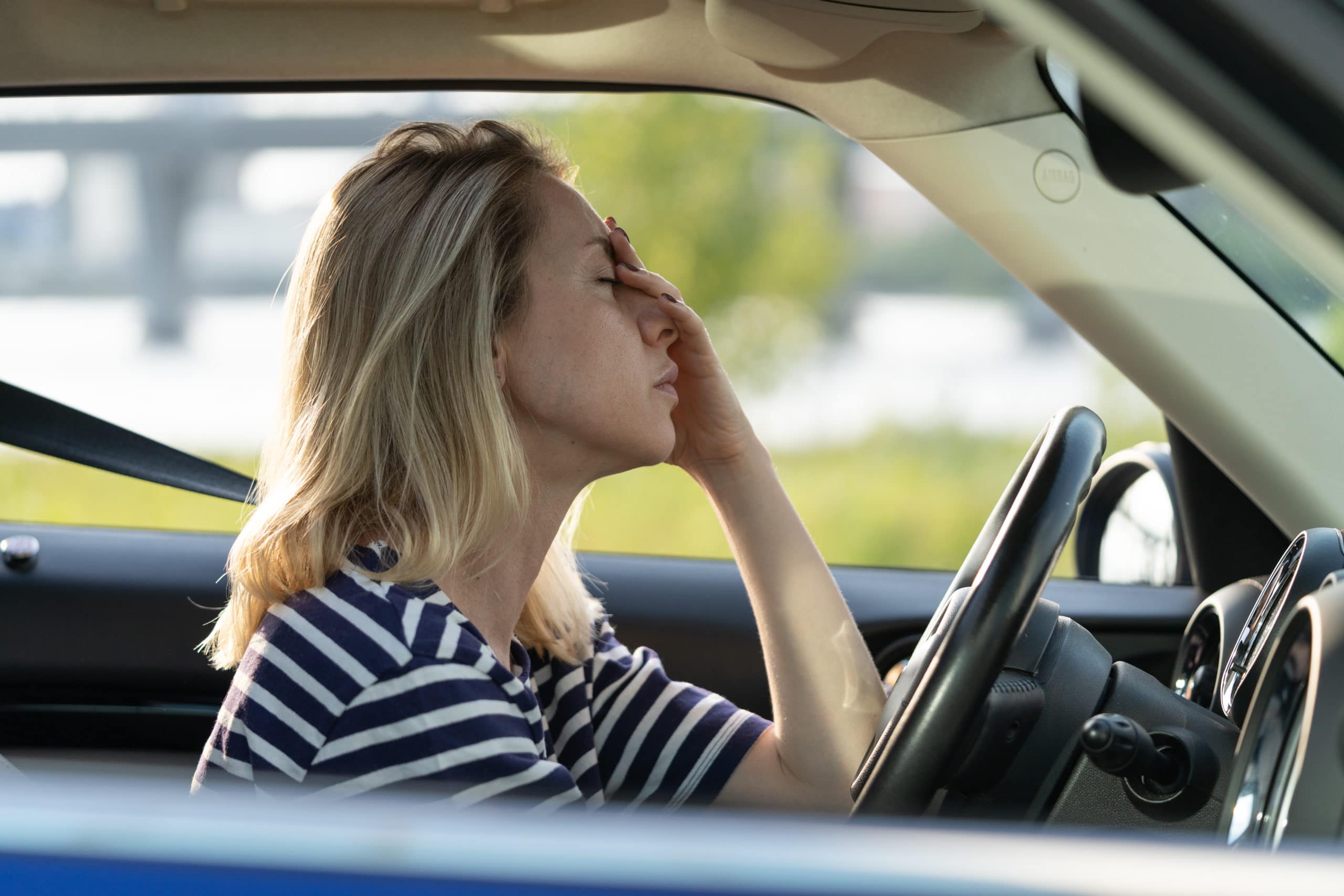 müde Fahrerin berührt Nase und Stirn beim Autofahren