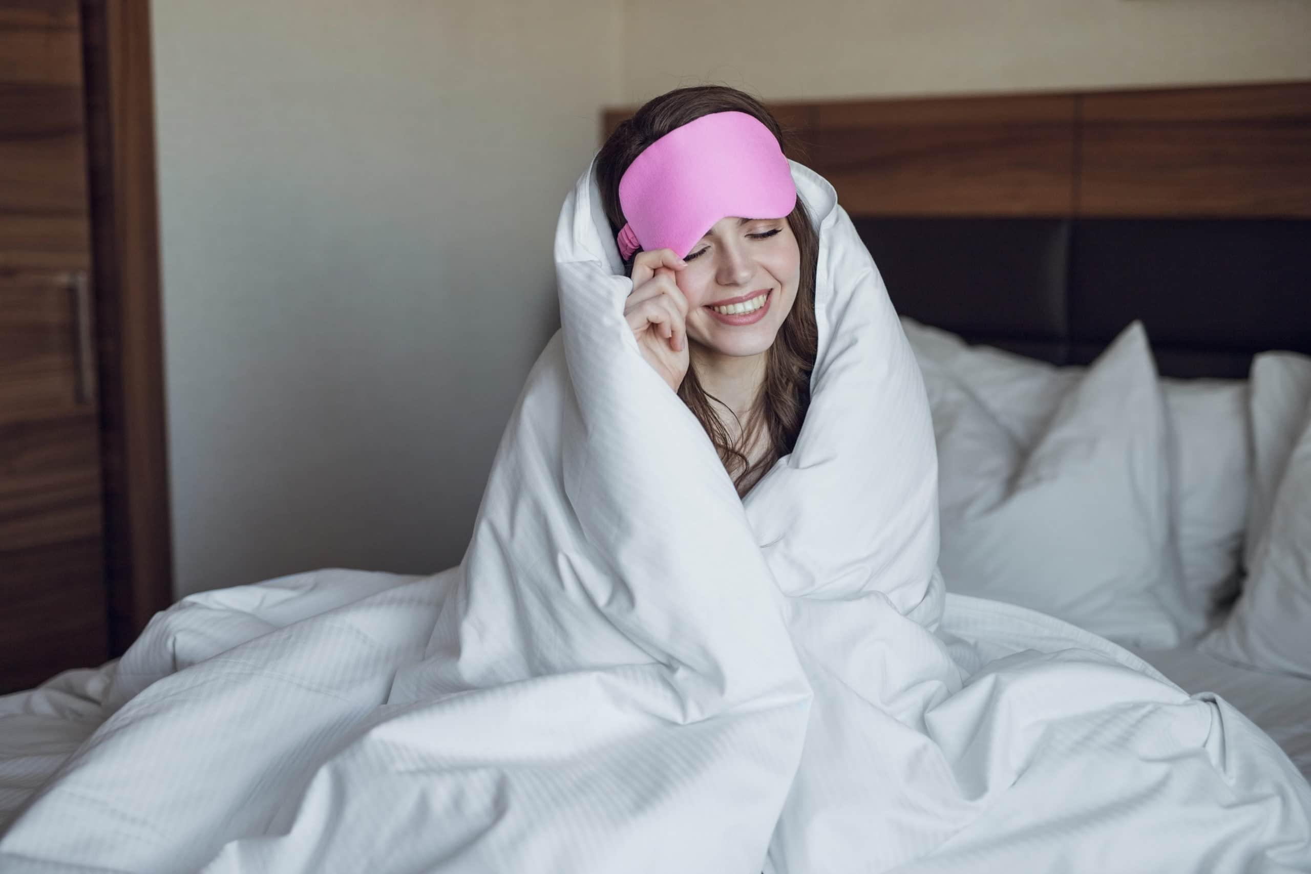 Frau mit Schlafmaske im Hotelbett