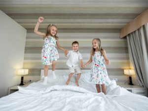 Glückliche Kinder, die auf dem Bett im Schlafzimmer springen, Spaß haben und spielen