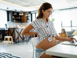 Müde schwangere Frau arbeiten von zu Hause am Computer