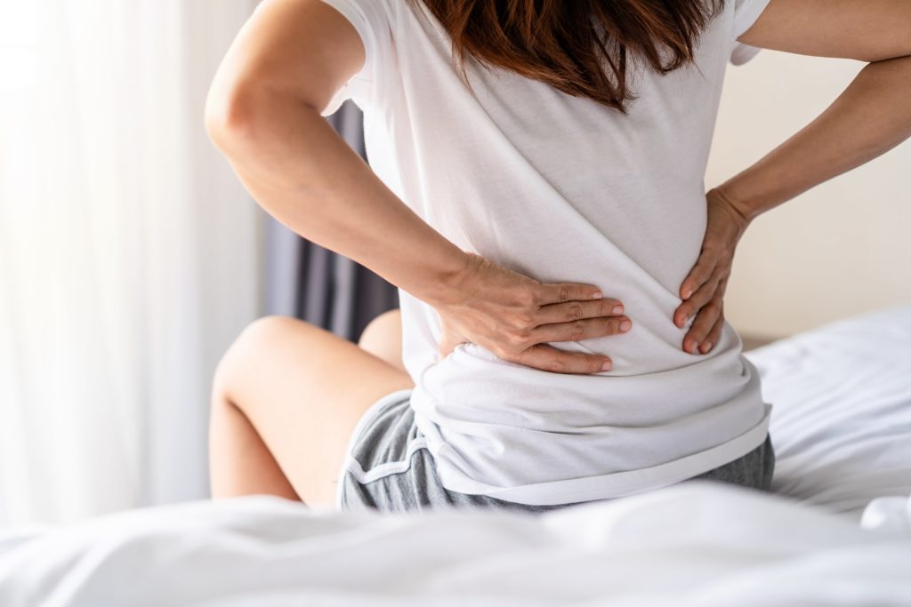 Frau leidet unter Rückenschmerzen auf dem Bett