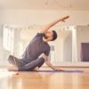 Hübscher junger Mann macht Dehnübungen im Yoga-Studio