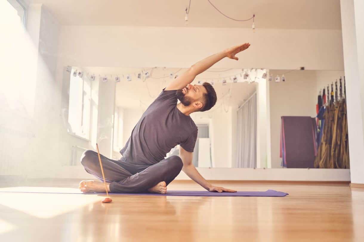 Hübscher junger Mann macht Dehnübungen im Yoga-Studio
