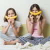 Schwestern benutzen Bananen für Smiley