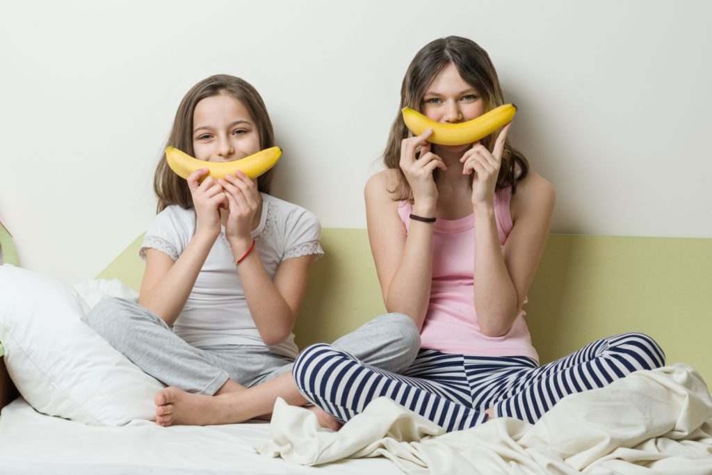 Schwestern benutzen Bananen für Smiley