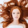 Frau mit schönen langen roten Haaren im Bett